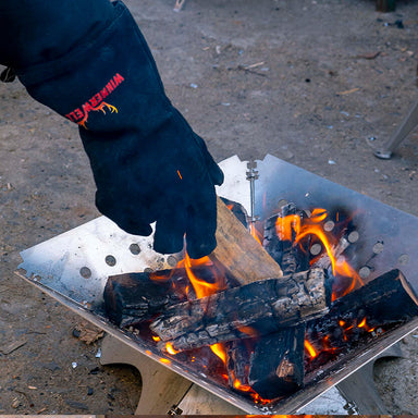 Winnerwell heat-resistant gloves being used to handle hot tent stove chimney pipe