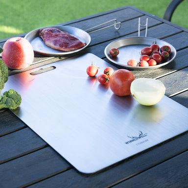 Winnerwell titanium cutting board in outdoor camp kitchen setting with fruit
