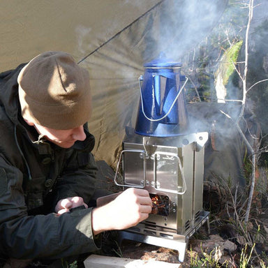 Man using Winnerwell Mini BBQ Smoker at riverside camp — 5-in-1 portable camping smoker at dusk